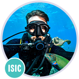 Potápěč v plné výstroji plave v průzračné modré vodě a fotí si selfie s želvou.